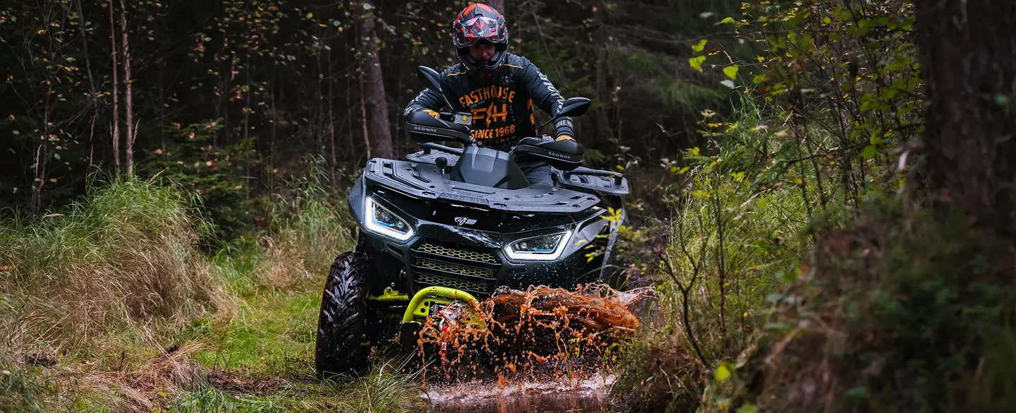 En förare på en Segway Snarler ATV i skogsterräng.